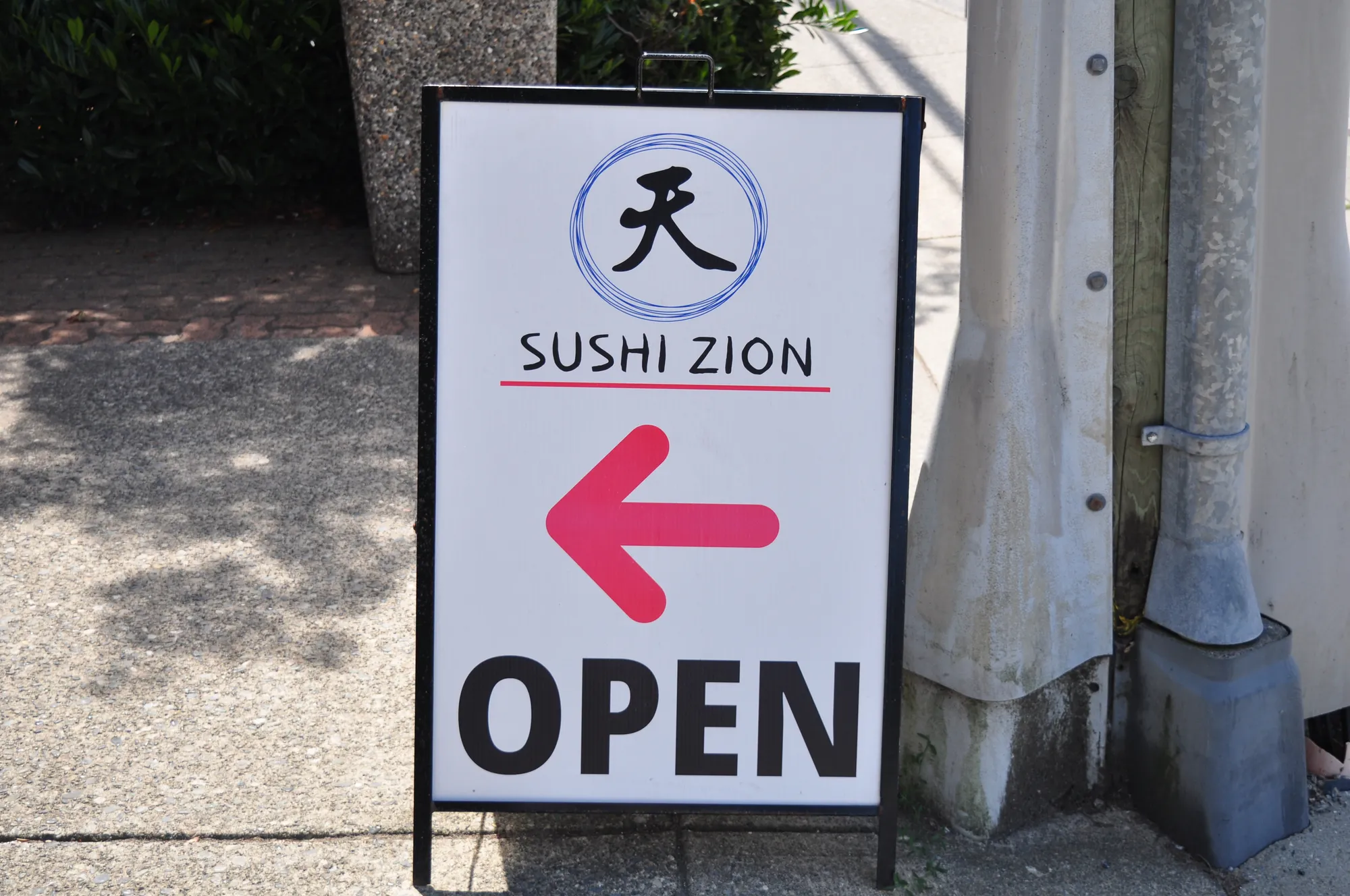 Sushi Zion A-frame sidewalk sign with open arrow in Vancouver