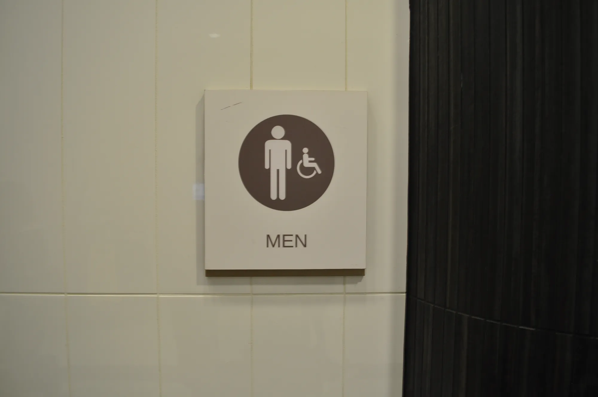 Accessible MEN washroom ADA sign on tiled wall in Vancouver