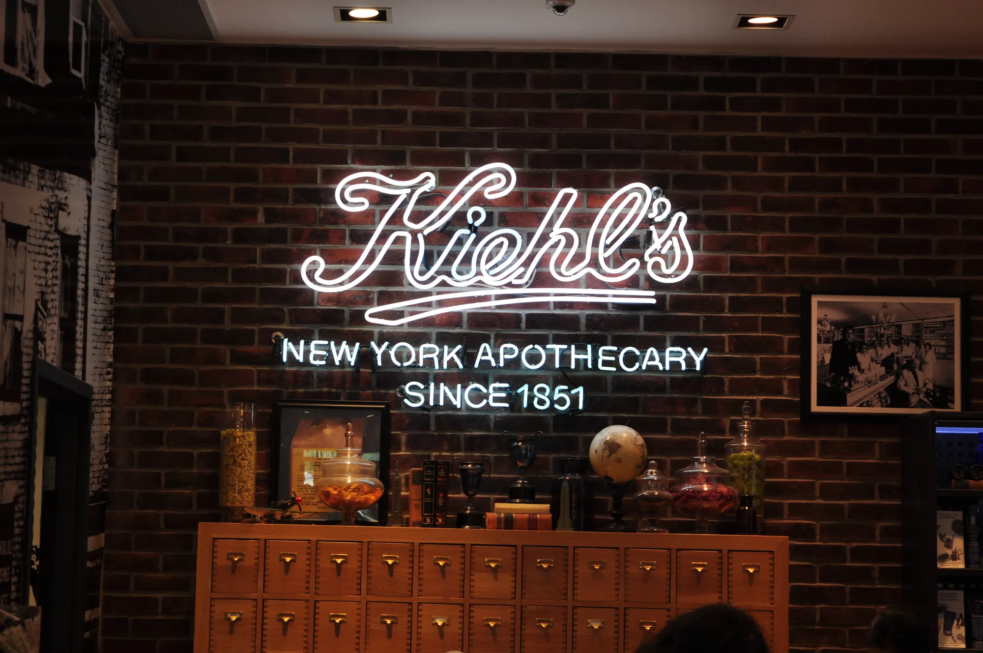 Kiehl's neon script sign on interior brick wall in Vancouver